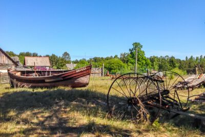 Old boat and fishing/farm equipment left out on land.