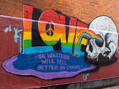 Graffiti in Dublin, Ireland. Words “Love or whatever will sell better on canvas” in rainbow paint with large white skull. © Nicholas Orloff