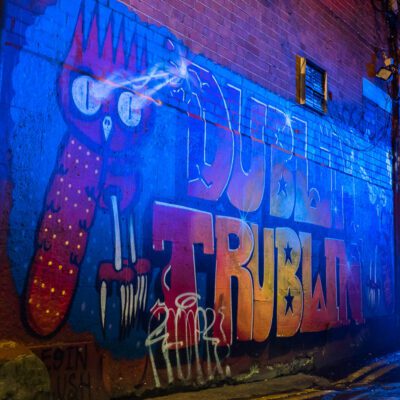 Electric blue image with lightening shooting out of a red creature’s eyes in a dark alleyway at night. Dublin Graffiti © Nicholas Orloff