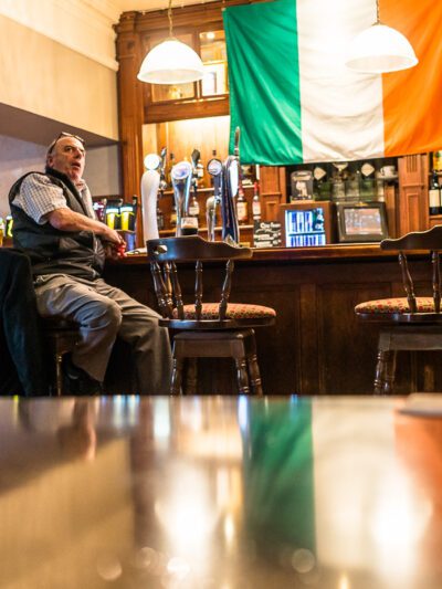 Irish flag hanging from ceiling of pub and reflecting off table below. © 2016 Nicholas Orloff.