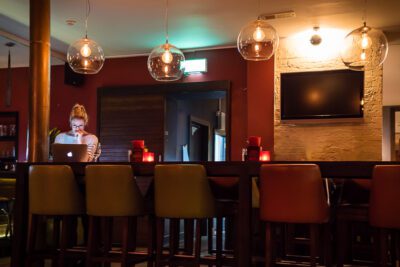 Woman using MacBook computer, sitting alone at long bar in a Dublin Gastropub. © 2016 Nicholas Orloff